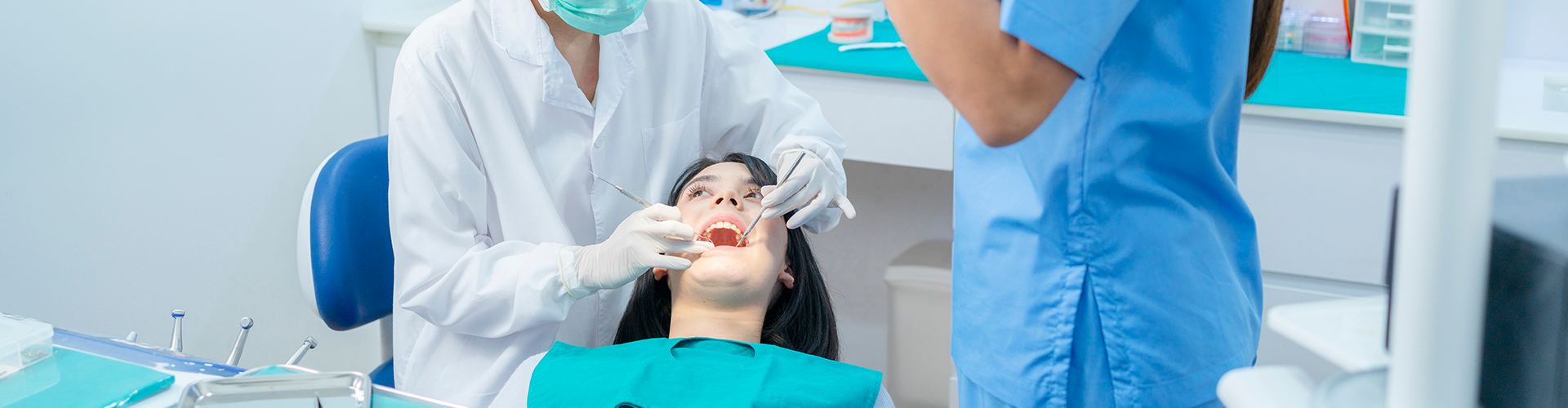 dental team using dental tools in woman's mouth